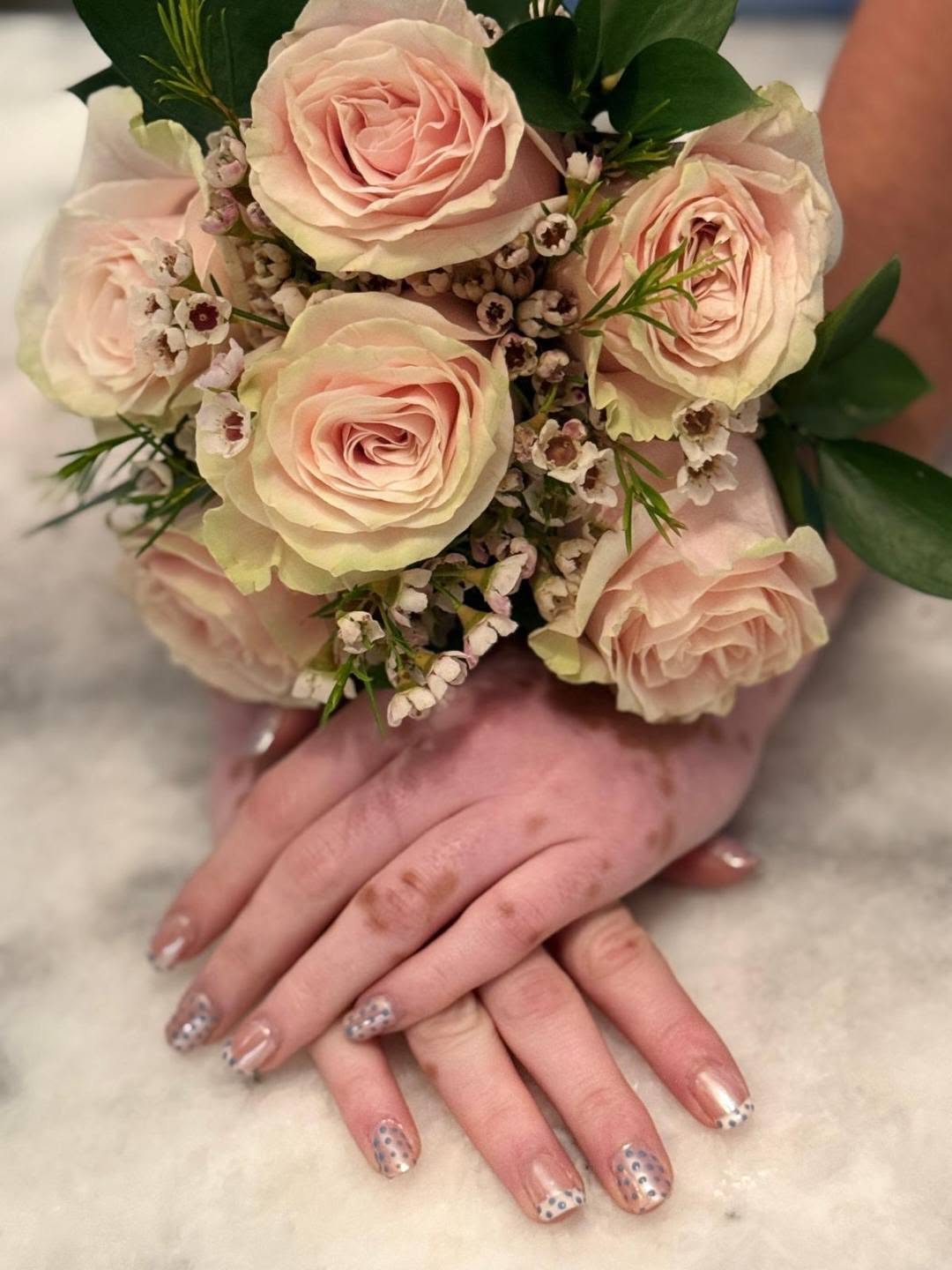 Bridal dotted french tip nails beside a rose bouquet